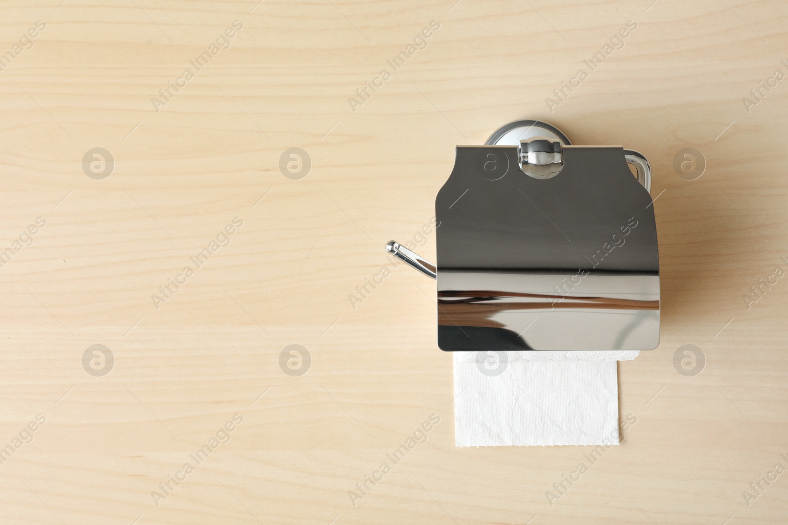 Photo of Holder with toilet paper roll on wooden background. Space for text