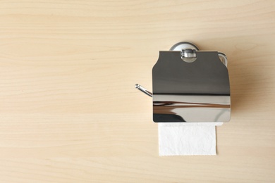 Holder with toilet paper roll on wooden background. Space for text