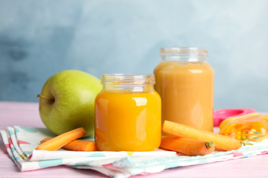 Photo of Healthy baby food in jars and fresh ingredients on pink wooden table against light blue background