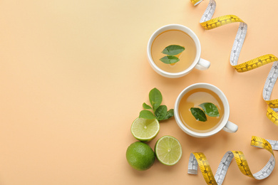 Flat lay composition with cups of diet herbal tea and measuring tape on orange background, space for text