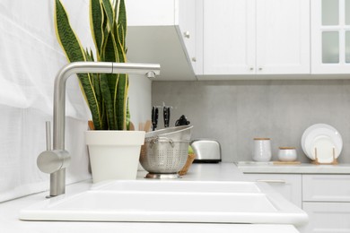 Photo of Modern sink and water tap in kitchen. Interior design