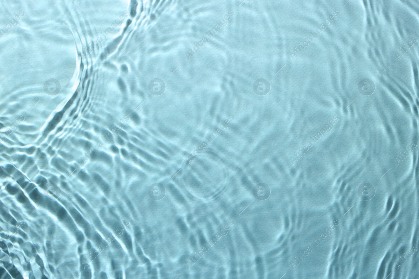 Image of Rippled surface of clear water on light blue background, top view