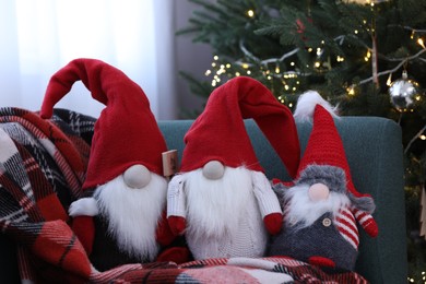 Photo of Funny decorative gnomes on sofa near Christmas tree