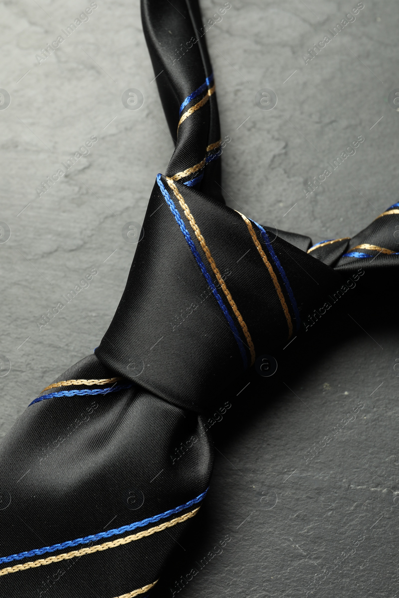 Photo of One striped necktie on grey textured table, top view