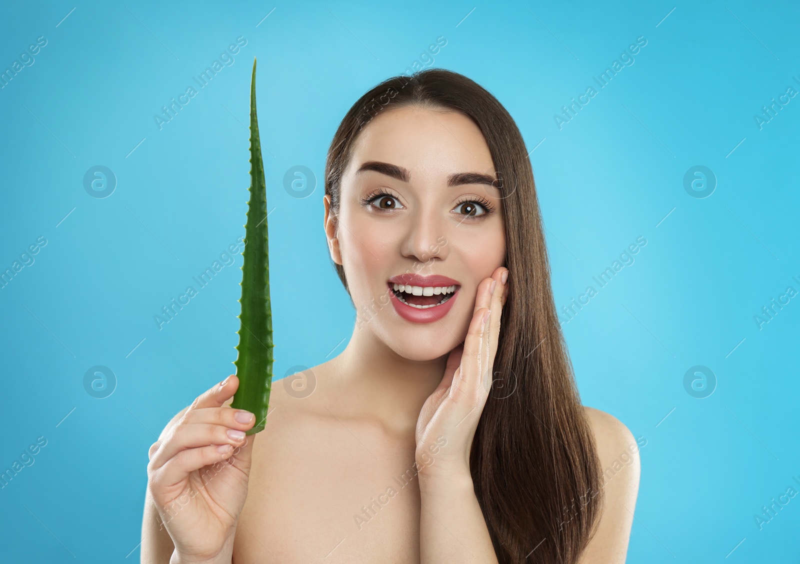 Photo of Emotional young woman with aloe vera leaf on light blue background