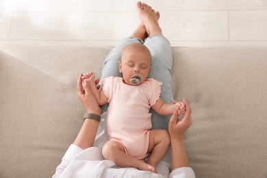 Photo of Mother with her cute sleeping baby on sofa indoors, top view