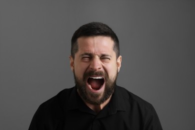 Personality concept. Emotional man screaming on grey background