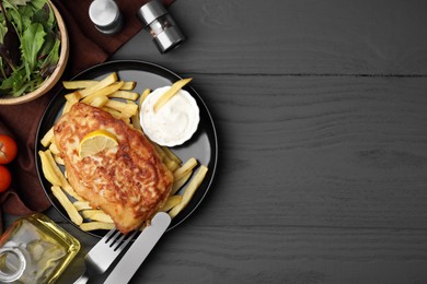 Photo of Tasty soda water battered fish, potato chips, sauce and lemon slice served on dark wooden table, flat lay. Space for text