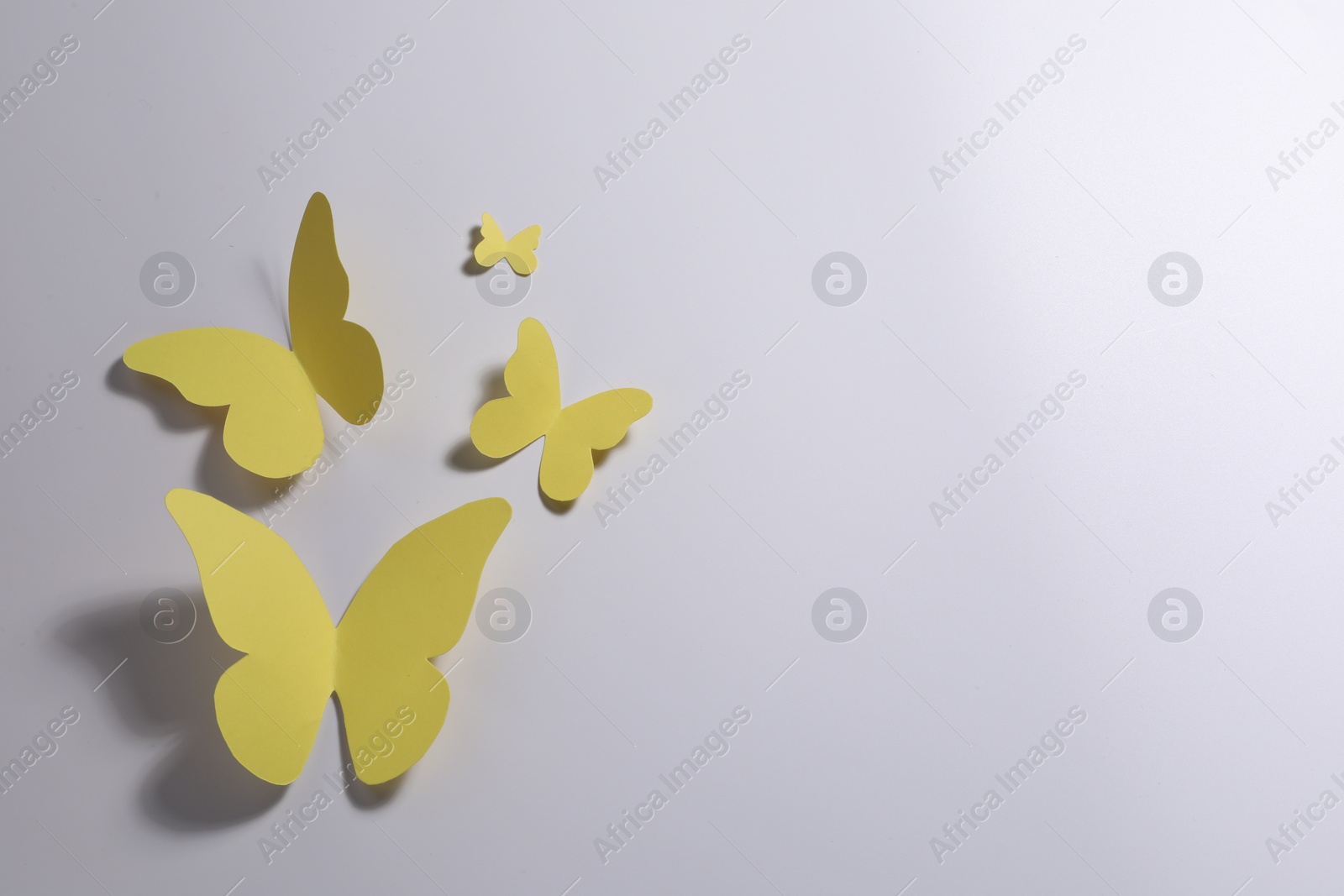 Photo of Yellow paper butterflies on light background, top view. Space for text