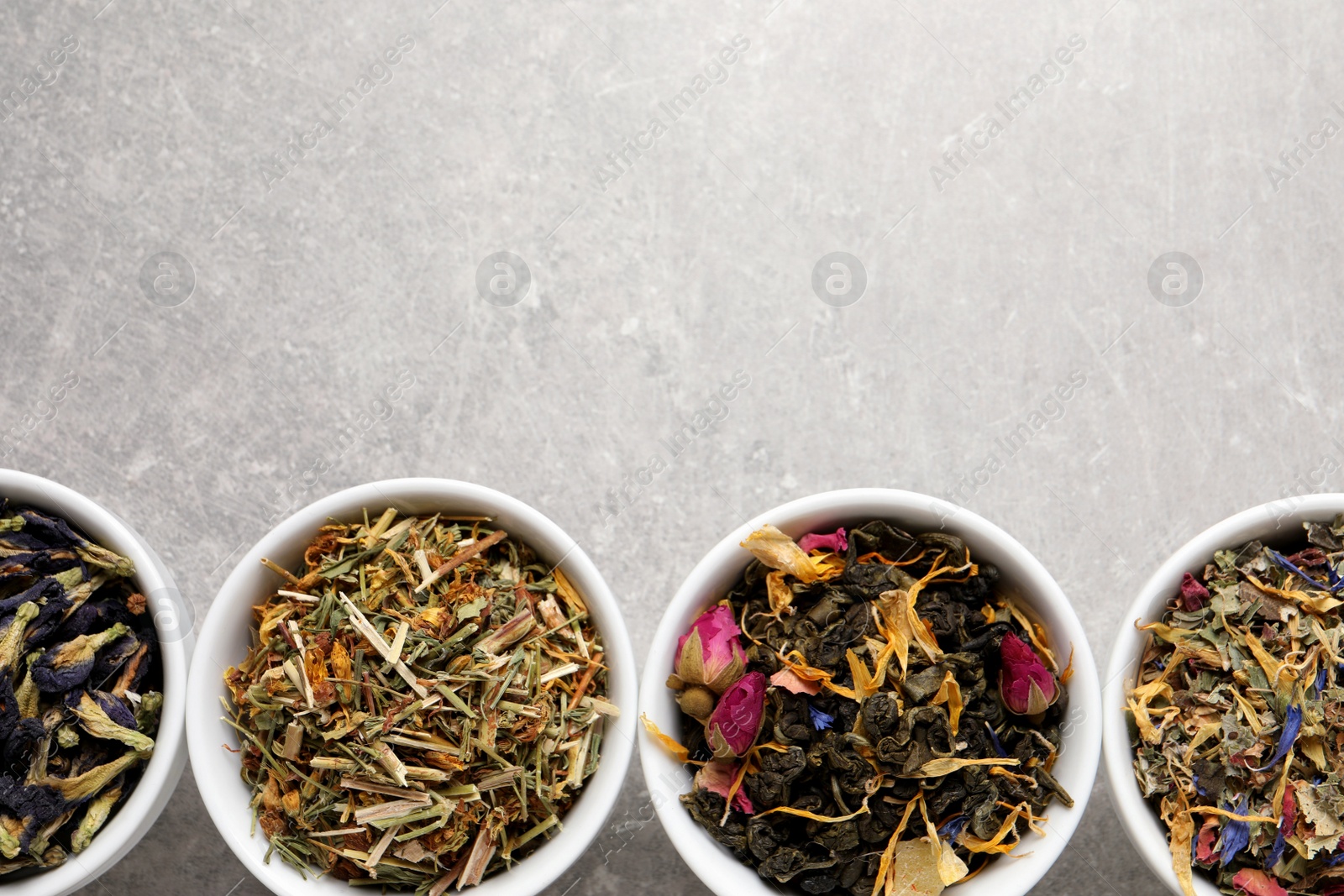 Photo of Flat lay composition with different dry teas on light grey table, space for text