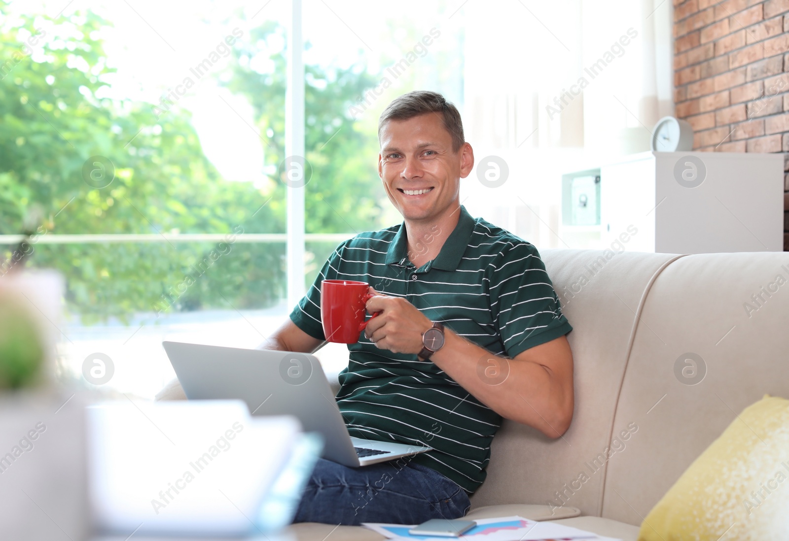 Photo of Young man working with laptop at home