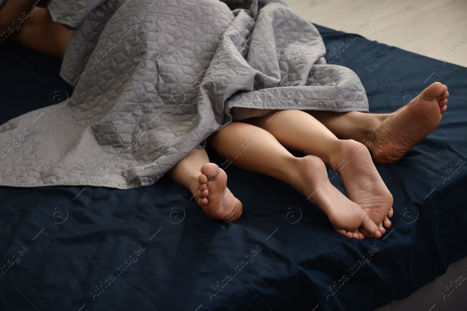 Photo of Passionate couple having sex on bed, closeup of legs