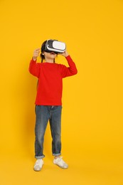 Photo of Little girl using virtual reality headset on yellow background