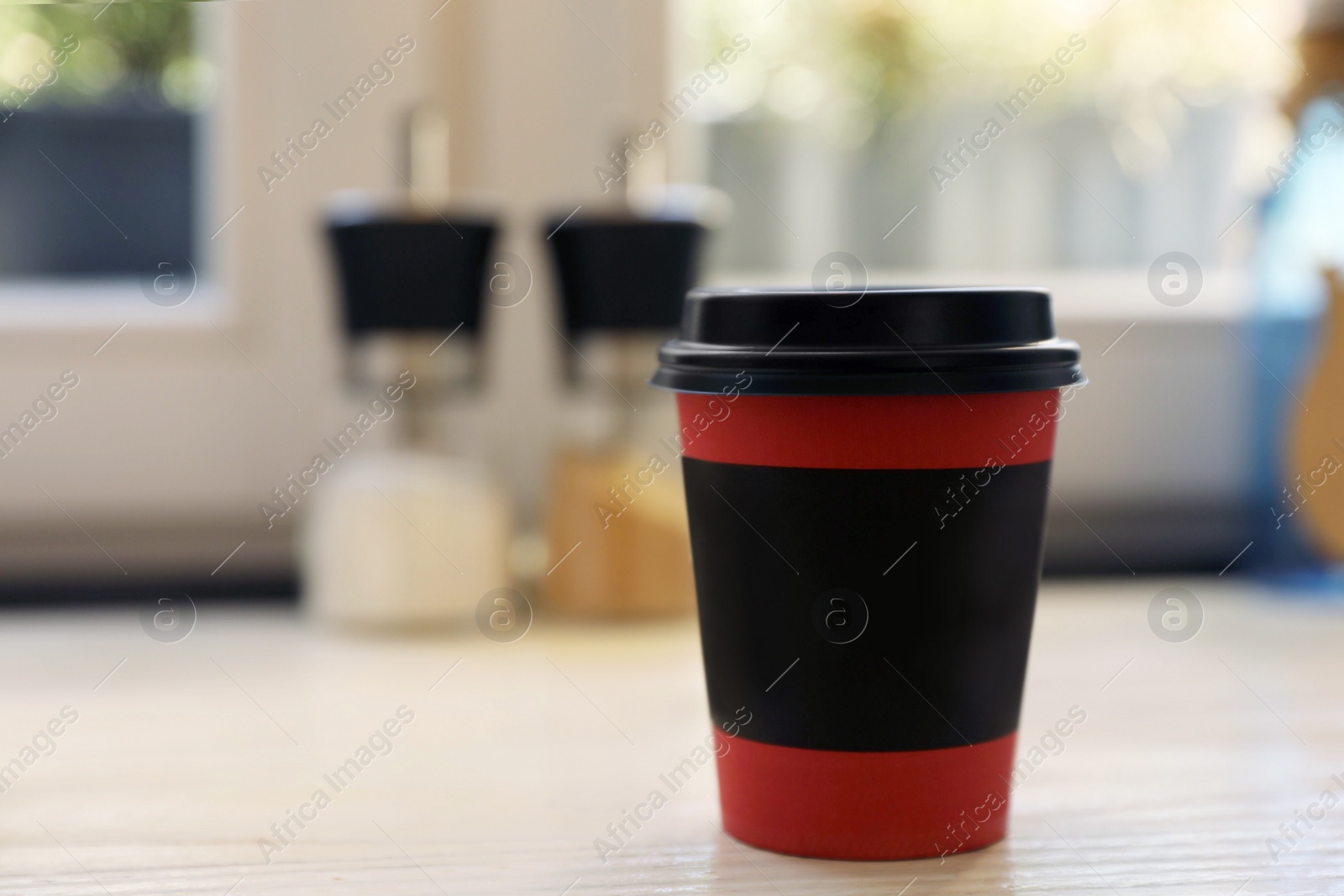 Photo of Hot coffee in takeaway paper cup on wooden table at cafe, space for text