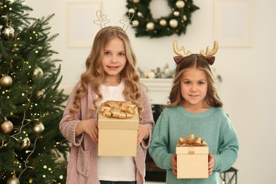 Photo of Portrait of cute little girls with Christmas gifts at home