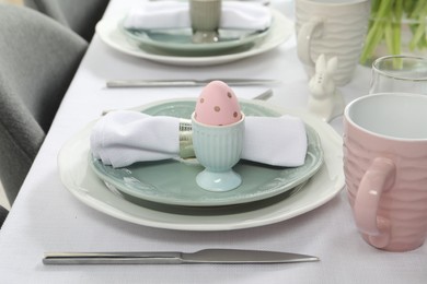 Photo of Easter celebration. Festive table setting with elegant dishware and painted eggs