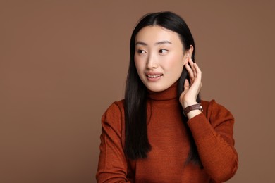 Portrait of smiling woman on brown background. Space for text