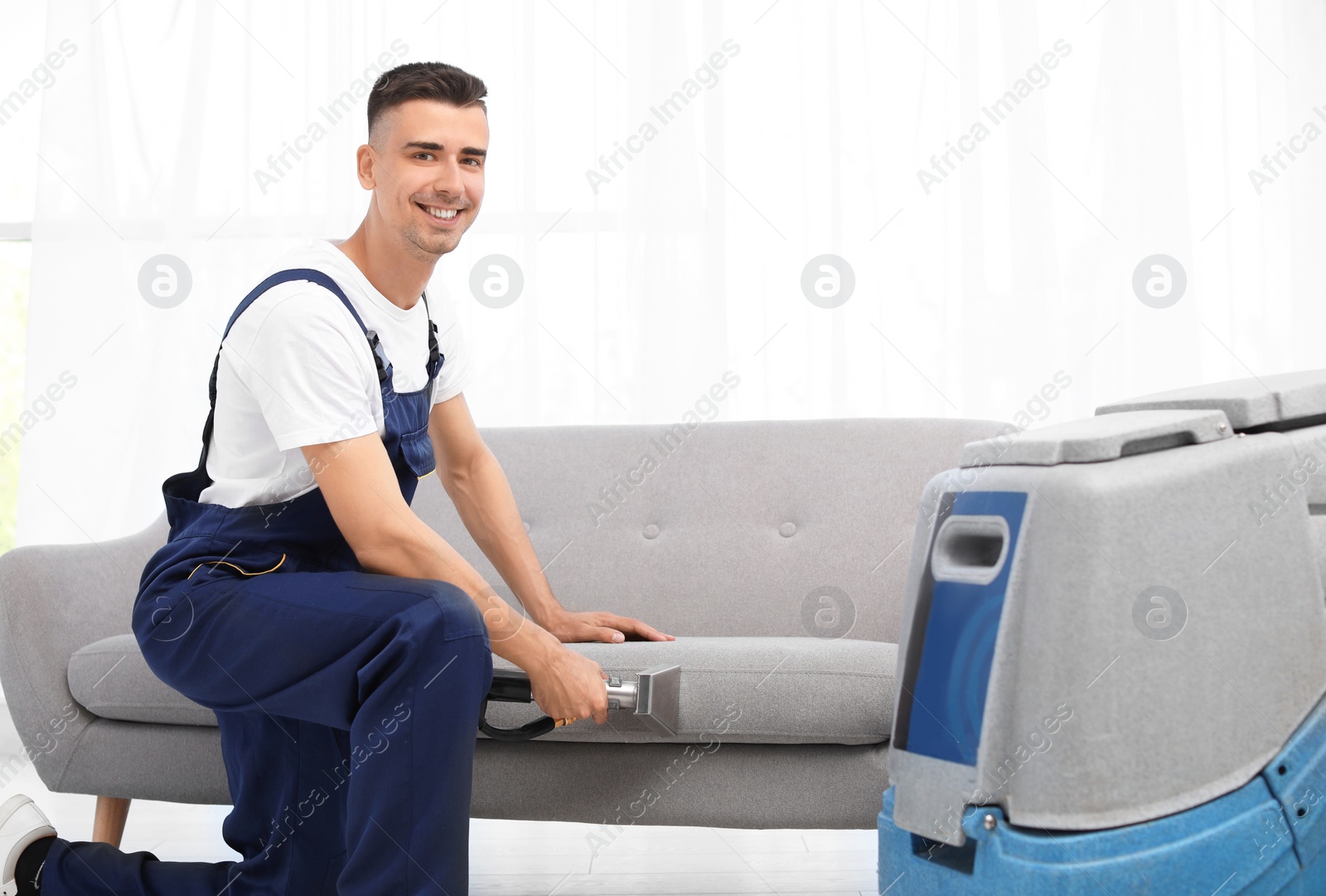 Photo of Dry cleaning worker removing dirt from sofa indoors
