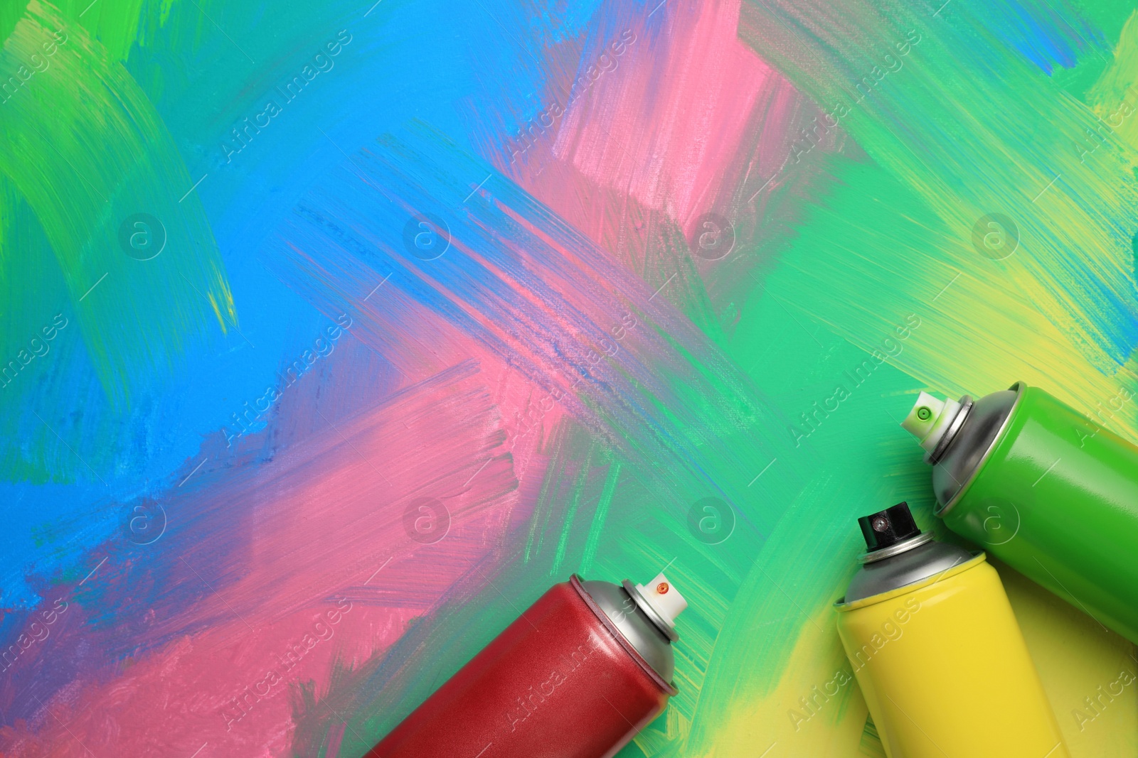 Photo of Cans of different spray paints on color background, flat lay with space for text. Graffiti supplies