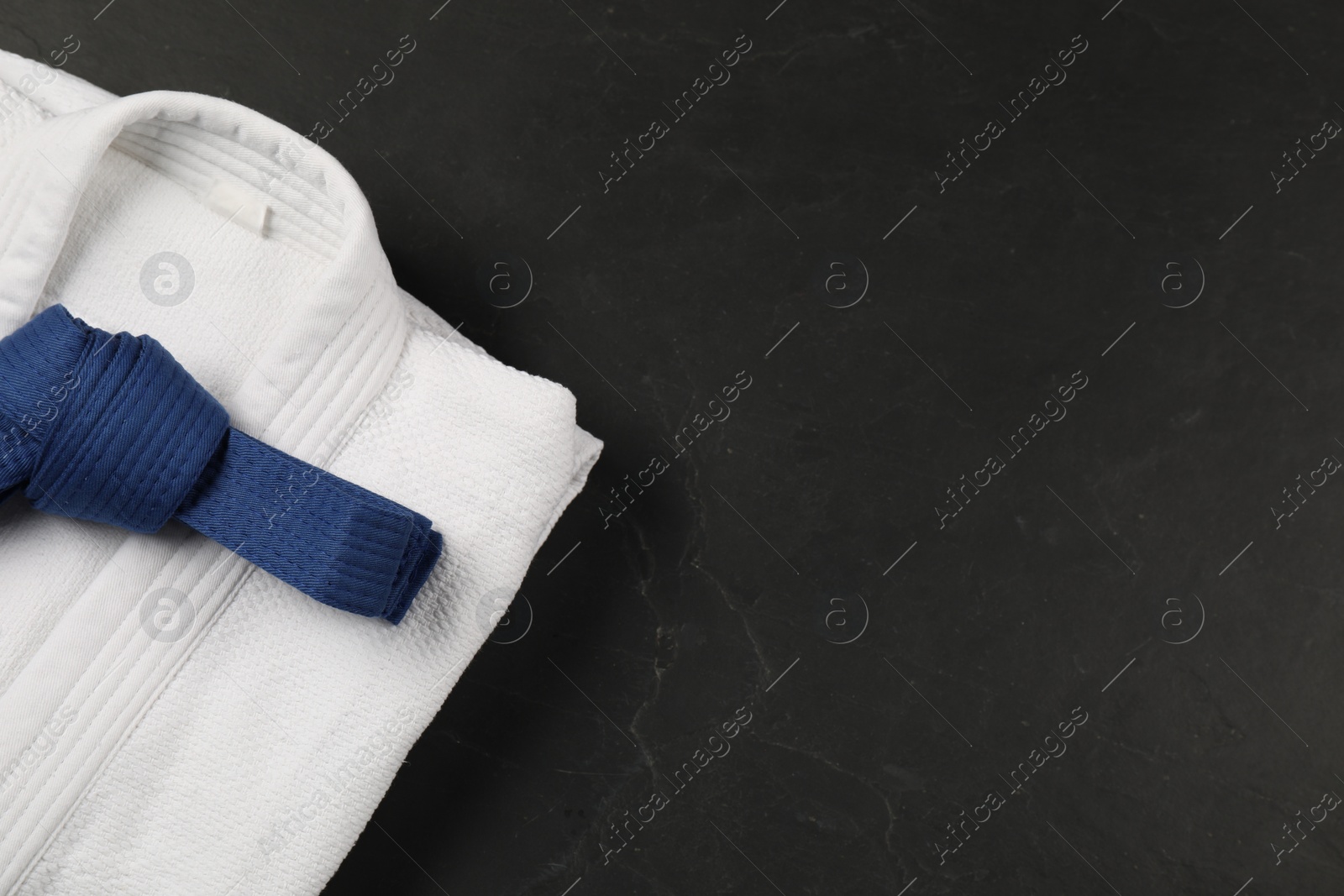 Photo of Blue karate belt and white kimono on gray background, top view. Space for text