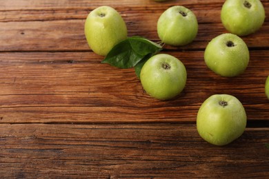 Photo of Fresh ripe green apples with water drops on wooden table. Space for text