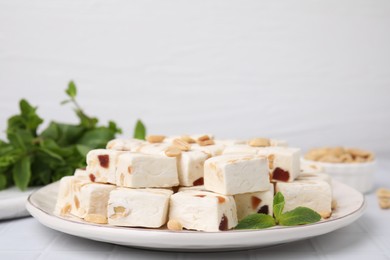 Pieces of delicious nutty nougat on plate, closeup