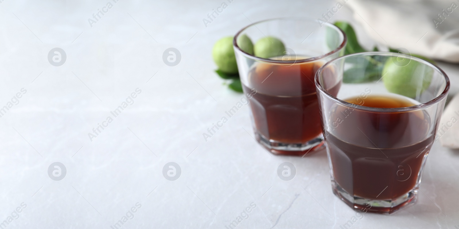 Image of Delicious liqueur and fresh walnuts on light table, closeup with space for text. Banner design