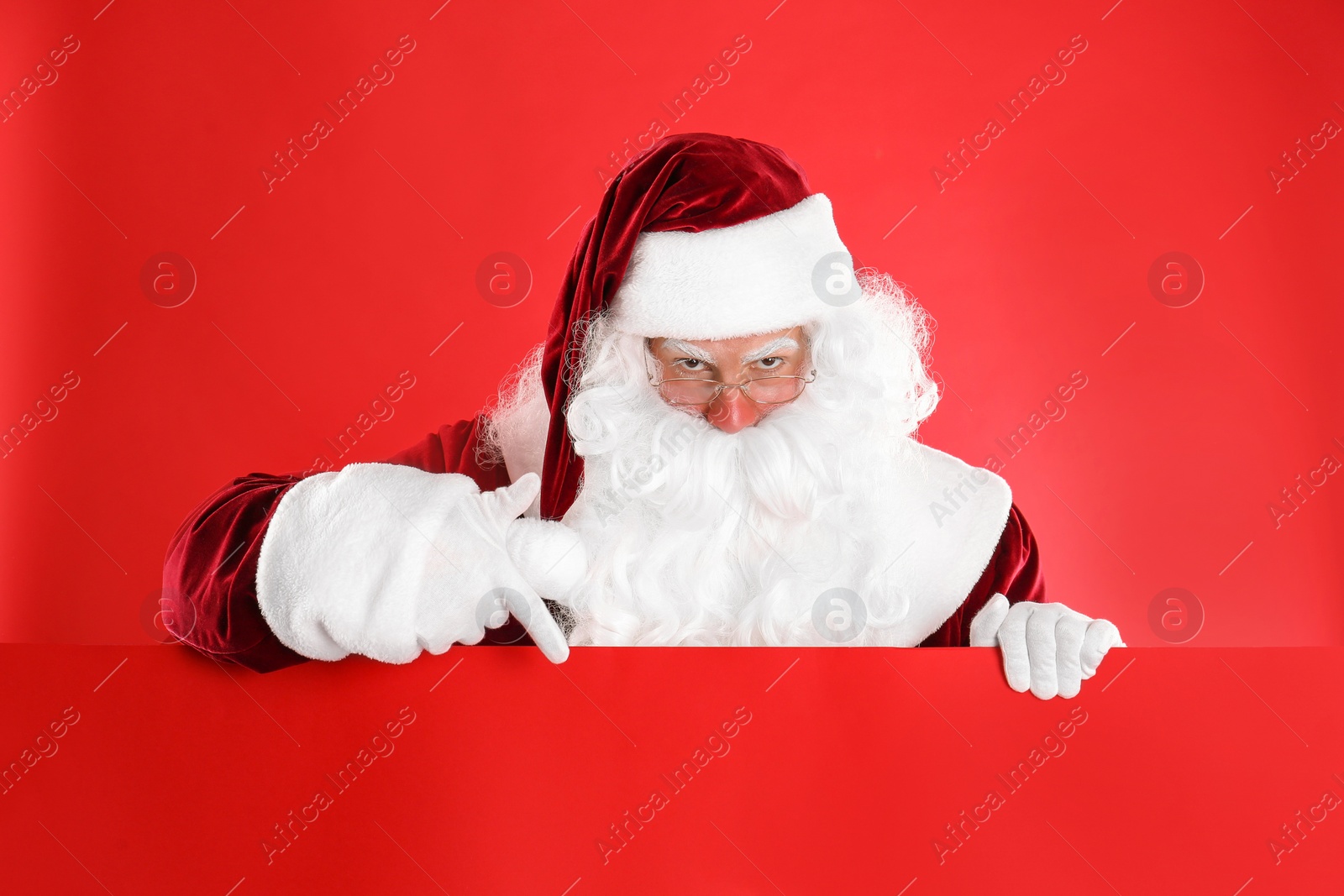 Photo of Santa Claus holding empty banner on red background