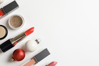 Flat lay composition with makeup products and Christmas decor on white background. Space for text