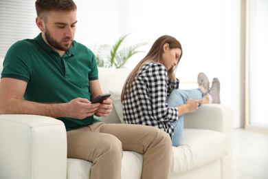 Photo of Couple addicted to smartphones at home. Relationship problems