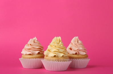 Tasty cupcakes with cream on pink background