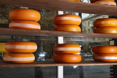 Display with different types of cheeses against window in store