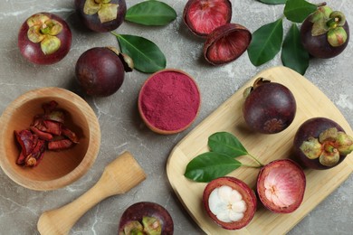 Purple mangosteen powder and fruits on grey marble table, flat lay