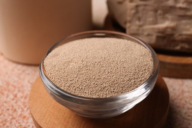 Dry granulated yeast on orange textured table, closeup