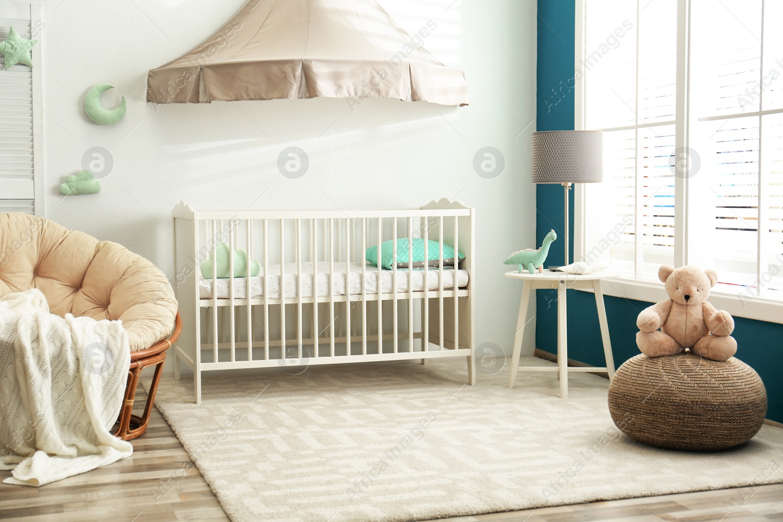 Photo of Cute nursery interior with comfortable crib near white wall