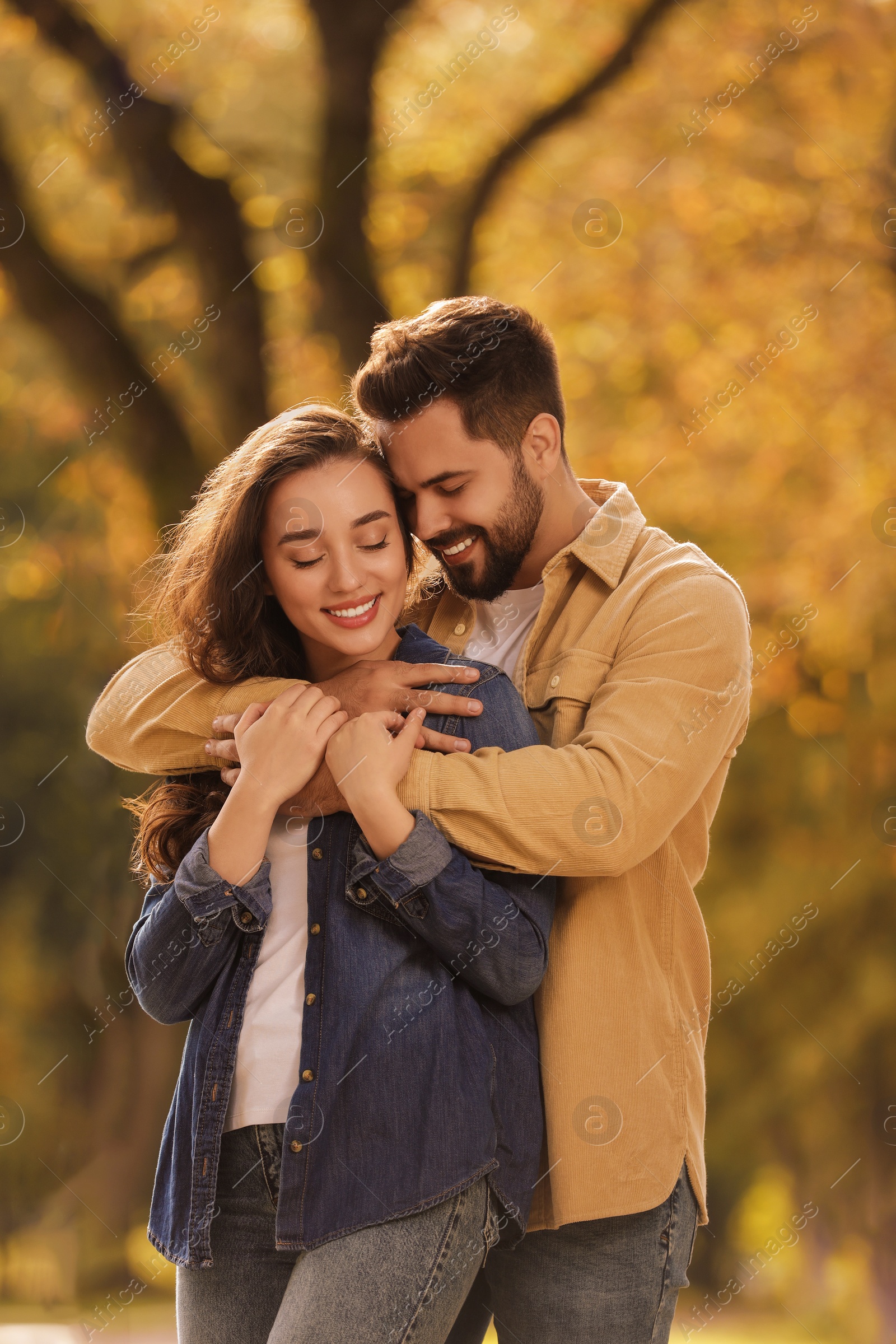 Photo of Beautiful young couple hugging in park on autumn day