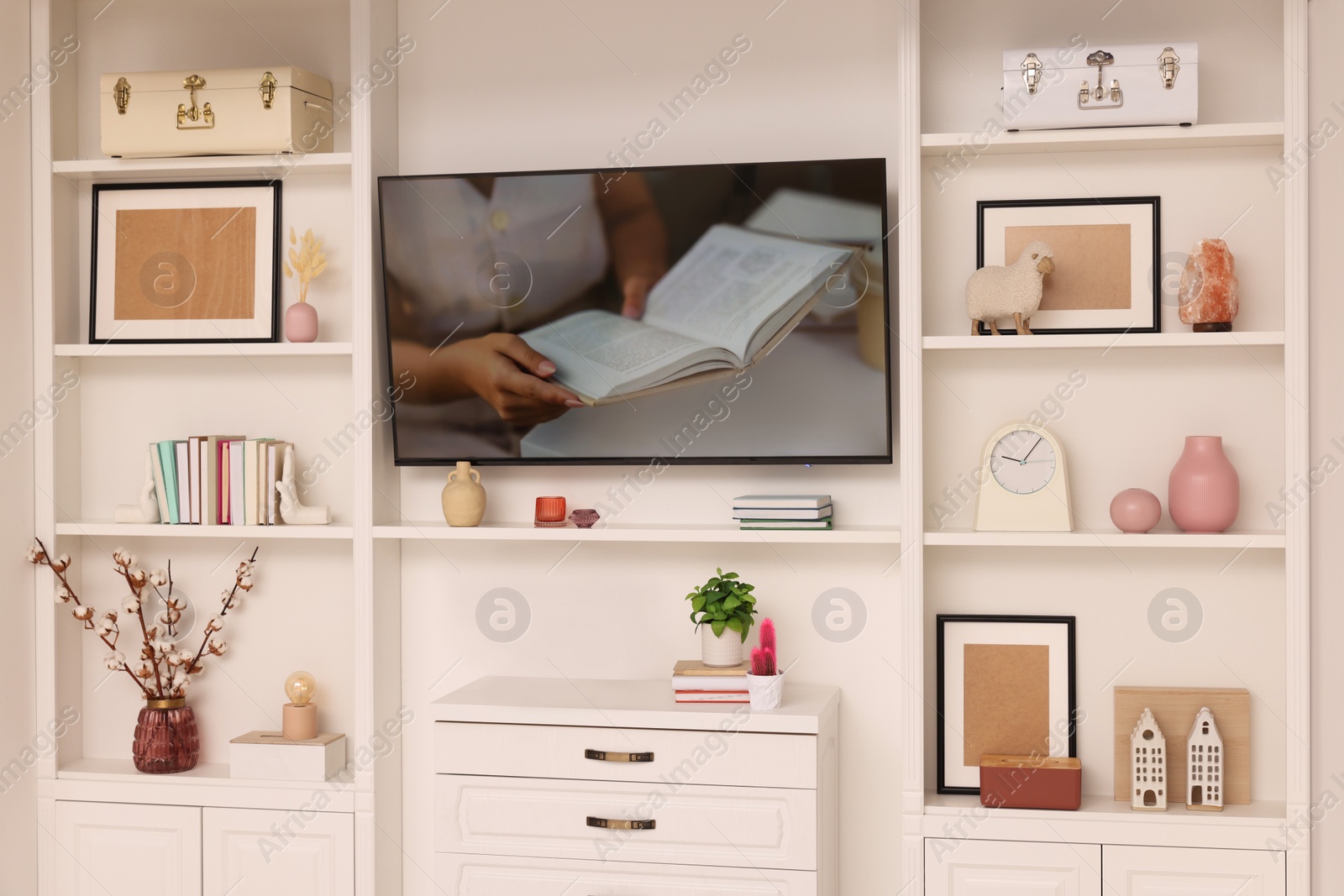 Photo of TV and shelves with different decor in room. Interior design