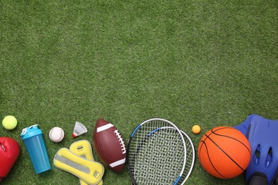Photo of Different sport equipment on green grass, flat lay. Space for text