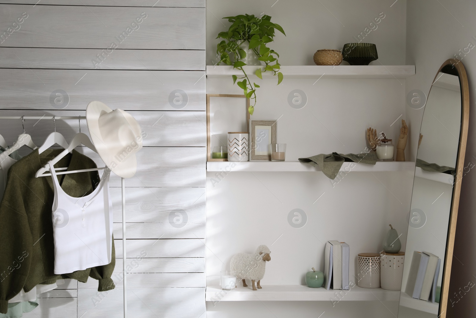 Photo of Rack with different stylish clothes and large mirror in dressing room