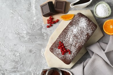 Photo of Tasty chocolate sponge cake and ingredients on light grey textured table, flat lay. Space for text