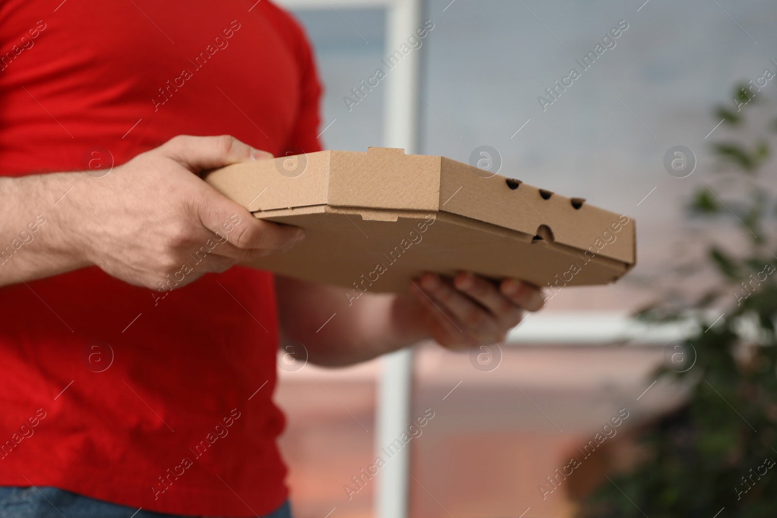 Photo of Courier with pizza box on blurred background, closeup