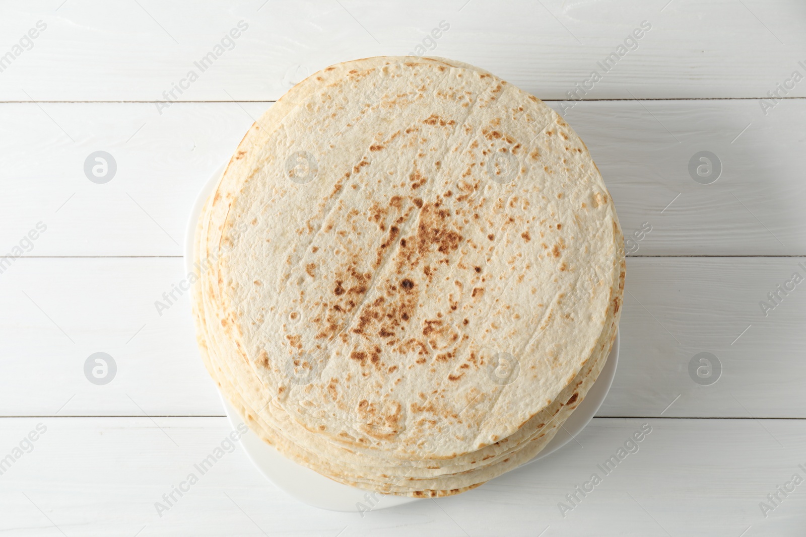 Photo of Stack of tasty homemade tortillas on white wooden table, top view