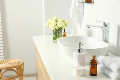 Bath accessories, sink and roses in bathroom
