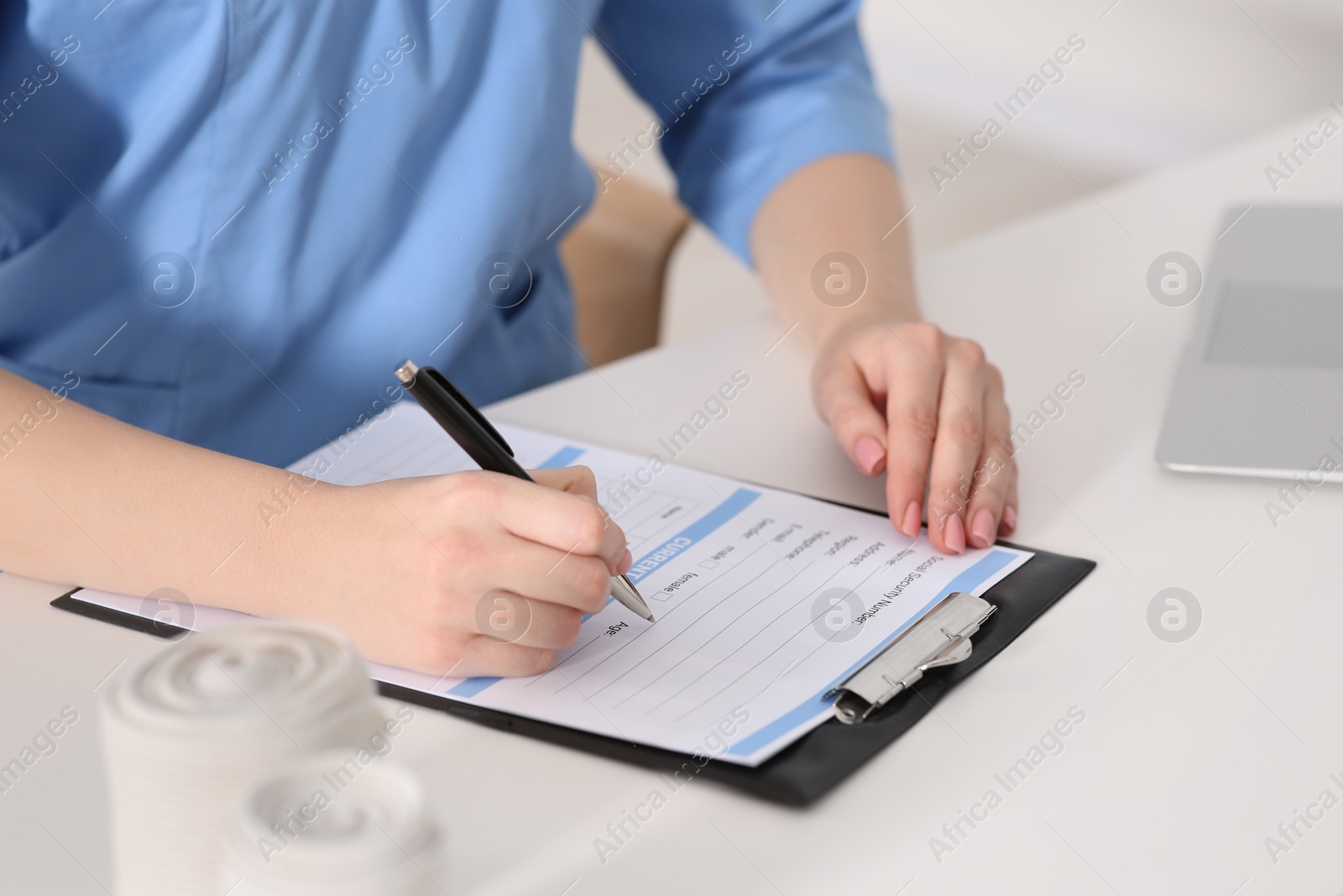 Photo of Doctor filling patient's medical card at table in clinic, closeup