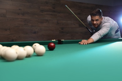 Photo of Handsome young man playing Russian billiard indoors. Space for text