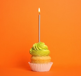 Birthday cupcake with candle on orange background