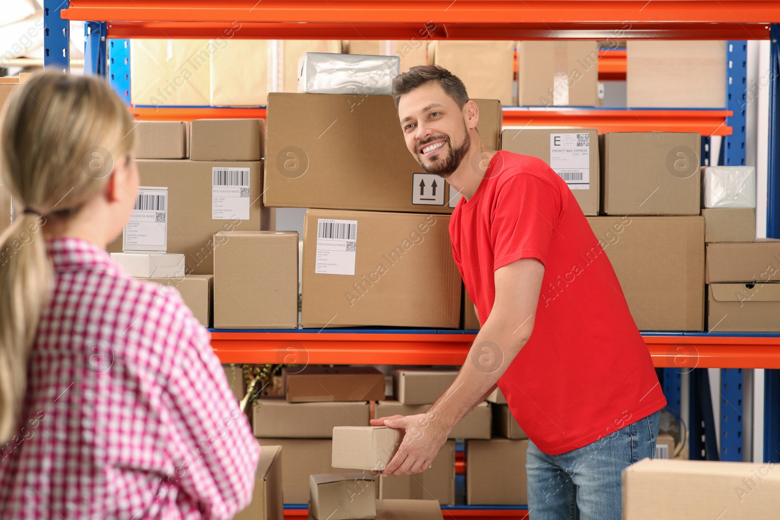 Photo of Woman and worker taking parcel from rack at post office