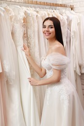 Young woman choosing wedding dress in salon