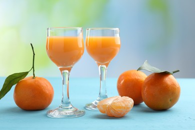 Delicious tangerine liqueur and fresh fruits on light blue wooden table