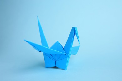 Origami art. Handmade paper crane on light blue background